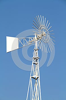 White water pumping wind mill on blue sky background