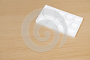 White watercolor palette. Empty watercolor tray isolated on wood background. White paint palette