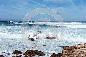 White waves hitting rocks on the ocean shore