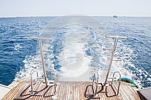 White waves from the ship engine and brown boards of the stern