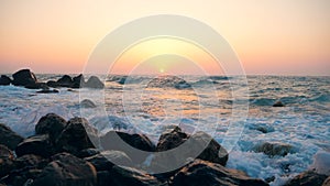 White waves splashing on rocks on a coastline, slow motion.