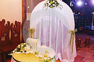 White wedding altar decorated with green ribbons stands in the r