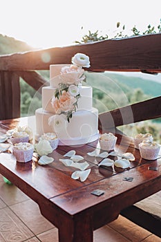 White wedding cake with flowers on a wooden table.