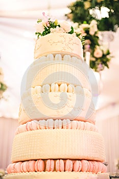 WHITE  WEDDING CAKE AT IMPRESSIVE COLOURFUL VENUE WITH BEAUTIFUL CANDY TABLES, FLORAL GREEN DECORATION, BLURRED BACKGROUND, YELLOW