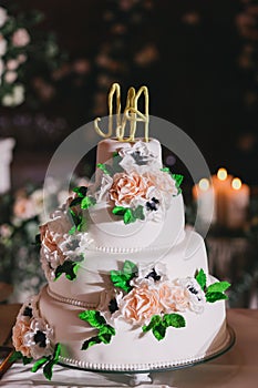 White wedding cake with mastic, decorated with roses and letters