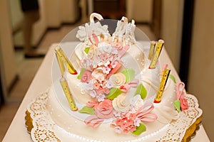 White wedding cake and pink thetas with figures of swans