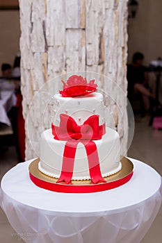 White wedding cake with red ribbons