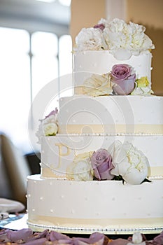 White wedding cake with yellow, white, and purple flowers. 4 tiers - wedding cake series photo