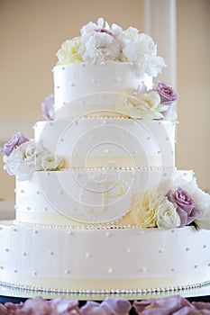 White wedding cake with yellow, white, and purple flowers. wedding cake series