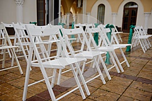 White wedding chairs with emerald ribbon on each side of archway outdoods, copy space.  Empty wooden chairs.