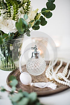 White wedding decor, perfume, pearl beads and bouquet of flowers