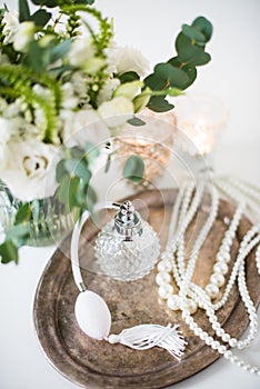White wedding decor, perfume, pearl beads and bouquet of flowers