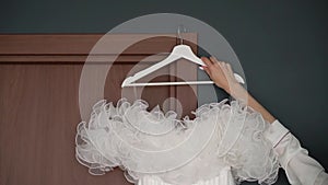 A white wedding dress on a hanger in a room. Morning of the bride.