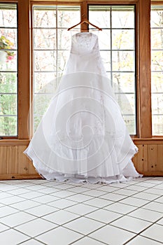 White Wedding Gown Hanging by Window