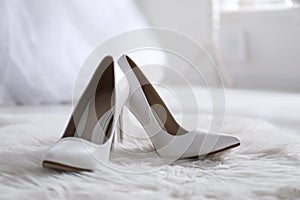 White wedding shoes on furry rug in room