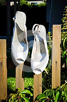 White wedding shoes hanging on fence