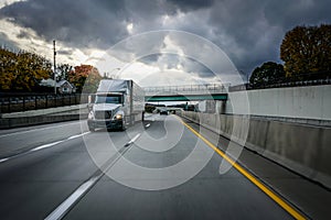 White 18 wheeler semi-truck on highway with storm clouds in the sky