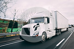 White 18 wheeler semi-truck on highway with motion blur