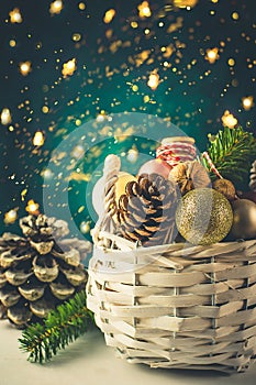 White wicker basket with Christmas ornaments golden balls, pine cones, nuts, gift wrapping ribbon. Christmas greeting card