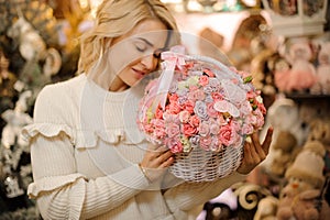 White wicker basket with small pink roses inside in hands of young beautiful blonde woman