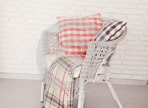 White wicker chair standing in an empty room in front of a brick