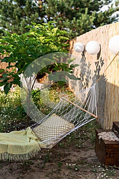 White wicker hammock with a pillow by the catalpa tree