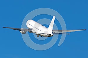 White wide-bodied aircraft takes off into the blue sky.