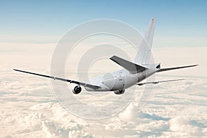 White wide body passenger aircraft flies in the air above the clouds