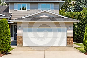 White wide garage door of residential house with concrete driveway in front