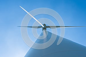 White wind turbine generating electricity on blue sky