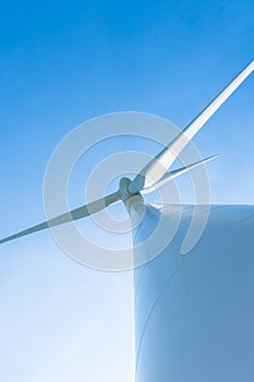 White wind turbine generating electricity on blue sky