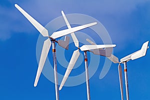 White wind turbines producing alternative energy on blue sky