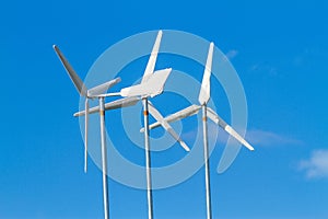 White wind turbines producing alternative energy on blue sky