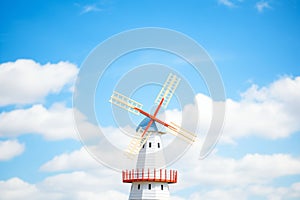 a white windmill against a blue sky with white clouds