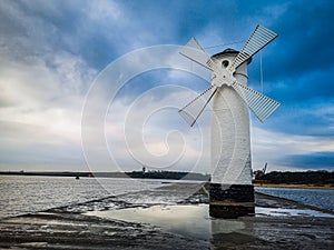 White Windmill at end of coast full of puddles near Baltic sea