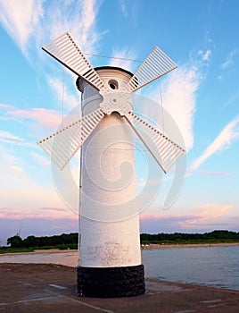 White windmill by sea on rocky coast. Seascape and landscape