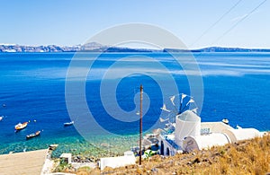 White windmill at Thirasia island coast and Santorini Greece