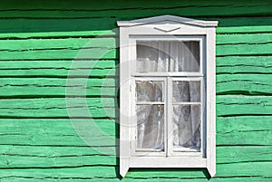 White window on the green wall of an old wooden house