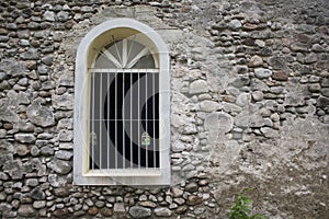 White window in old grey stone wall. Old medieval architecture.