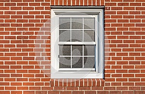 White window on a red brick wall, sun reflction on the glass