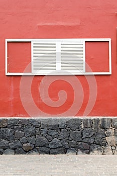 White window shutters on a red house wall
