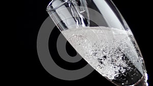 White wine being poured into a glass of black background. Slow motion