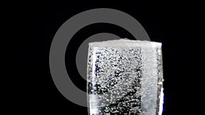 White wine being poured into a glass of black background. Slow motion