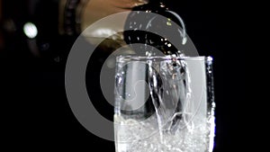 White wine being poured into a glass of black background. Slow motion
