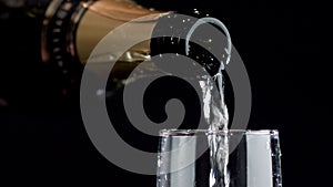 White wine being poured into a glass of black background. Slow motion