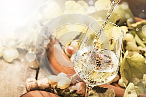 White wine being poured into a glass, vintage wood background, selective focus