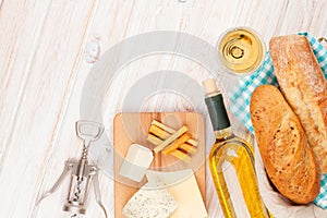 White wine, cheese and bread on white wooden table background