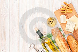 White wine, cheese and bread on white wooden table background