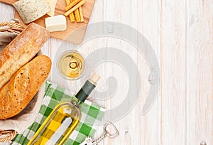 White wine, cheese and bread on white wooden table background