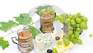 White wine, cheese and grapes on white table